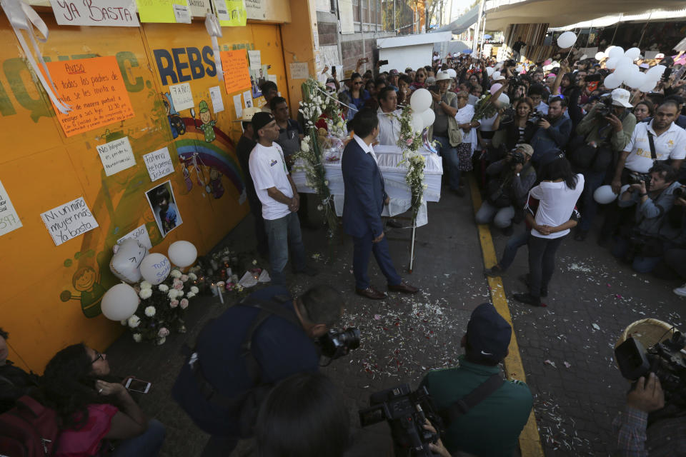 The casket of 7-year-old murder victim Fatima is placed at the gate of the primary school from where she was abducted, as her funeral procession walks to a church for a funeral Mass in Mexico City, Tuesday, Feb. 18, 2020. Fatima's body was found wrapped in a bag and abandoned in a rural area on Saturday. Five people have been questioned in the case, and video footage of her abduction exists. (AP Photo/Marco Ugarte)