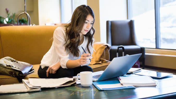 Businesswoman working at laptop in lobby.