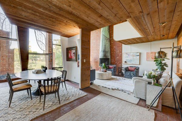 A harmonious blend of brick, wood, and glass awaits inside, where an open floor plan connects the living areas. A soaring patina fireplace underscores the grand sense of space.