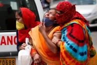 A woman is consoled after her husband died due to the coronavirus disease (COVID-19) outside a mortuary of a COVID-19 hospital in Ahmedabad