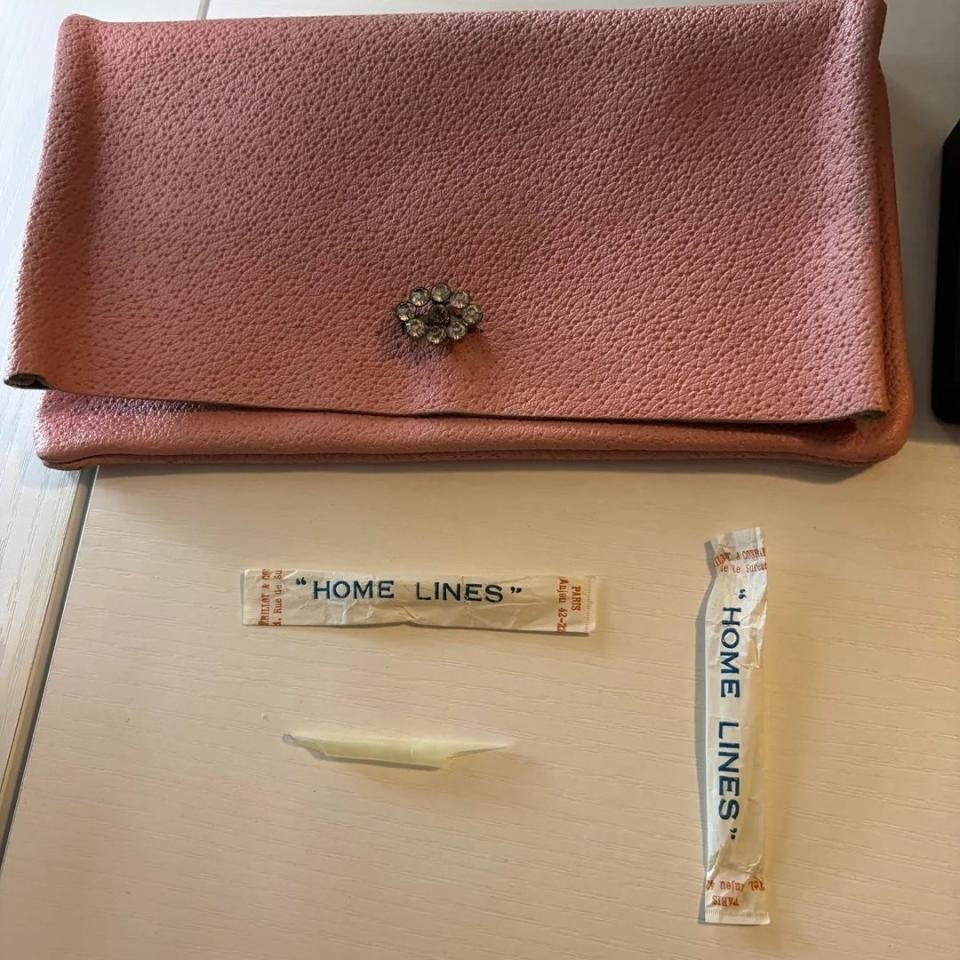 A pink clutch bag with a floral clasp, a toothpick and two unopened ones 