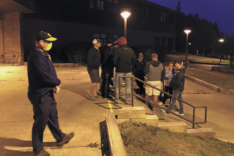 CORRECTS SOURCE TO HOMER NEWS - Homer High School Principal Douglas Waclawski, left, stands at the entrance to the local high school while residents show up in search of higher ground in the early morning hours of Wednesday, July 22, 2020 in Homer, Alaska, after a powerful earthquake shook the region late Tuesday evening. (Megan Pacer/Homer News via AP)