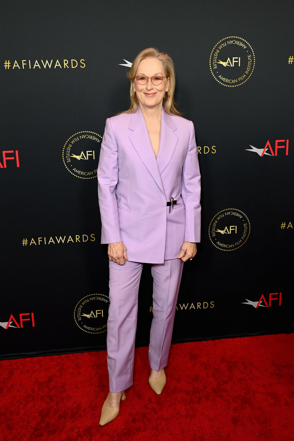Meryl in a suit standing on the AFI Awards red carpet