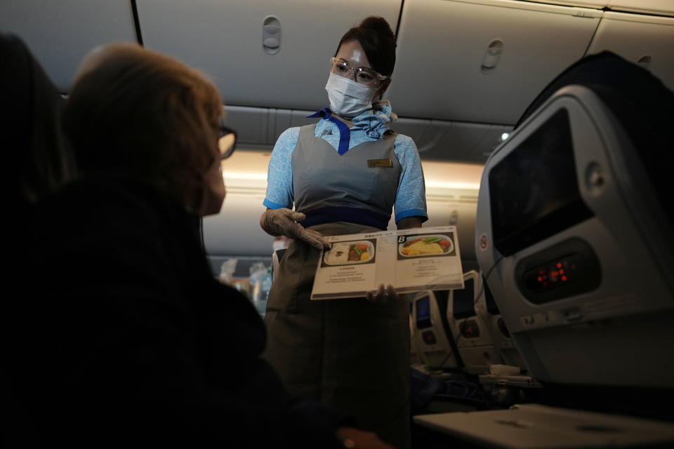 A flight attendant shows the food options on a flight to Tokyo from Frankfurt, Germany, Monday, July 19, 2021. (AP Photo/Natacha Pisarenko)