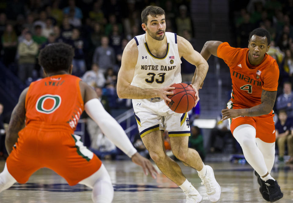 Notre Dame's John Mooney (33) looks to pass between Miami's Chris Lykes (0) and Keith Stone (4) during the second half of an NCAA college basketball game Sunday, Feb. 23, 2020, in South Bend, Ind. (AP Photo/Robert Franklin)