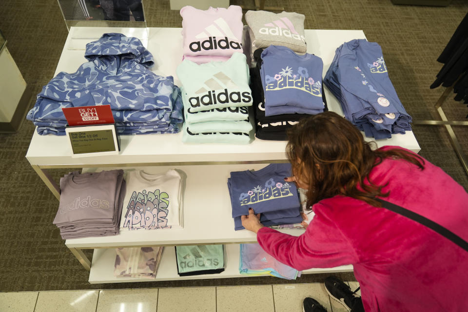 A merchandiser arranges clothing at a Kohl's store in Clifton, N.J., Friday, Jan. 26, 2024. A year ago, the store had tables featuring sweaters and shirts piled high in different colors and racks of different styles of dresses. Now, it boasts a more edited approach — tables have slim piles of knit shirts that focus on fewer colors, and many racks have been reduced to just three styles of dresses. (AP Photo/Seth Wenig)