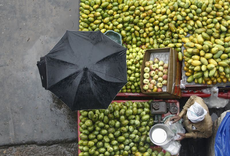 A vendor sells fruits during a heavy monsoon rain shower in New Delhi