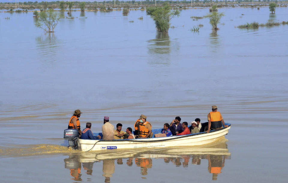 Pakistani army soldiers evacuate villagers from a flooded areas of Dadu, a district in Pakistan's southern Sindh province, Sunday, Aug. 9, 2020. Three days of heavy monsoon rains triggering flash floods killed at least dozens people in various parts of Pakistan, as troops with boats rushed to a flood-affected district in the country's southern Sindh province Sunday to evacuate people to safer places. (AP Photo/Pervez Masih)