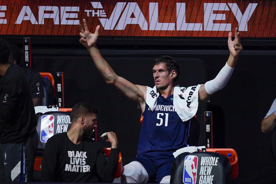 Dallas Mavericks center Boban Marjanovic with his hands raised on the bench.