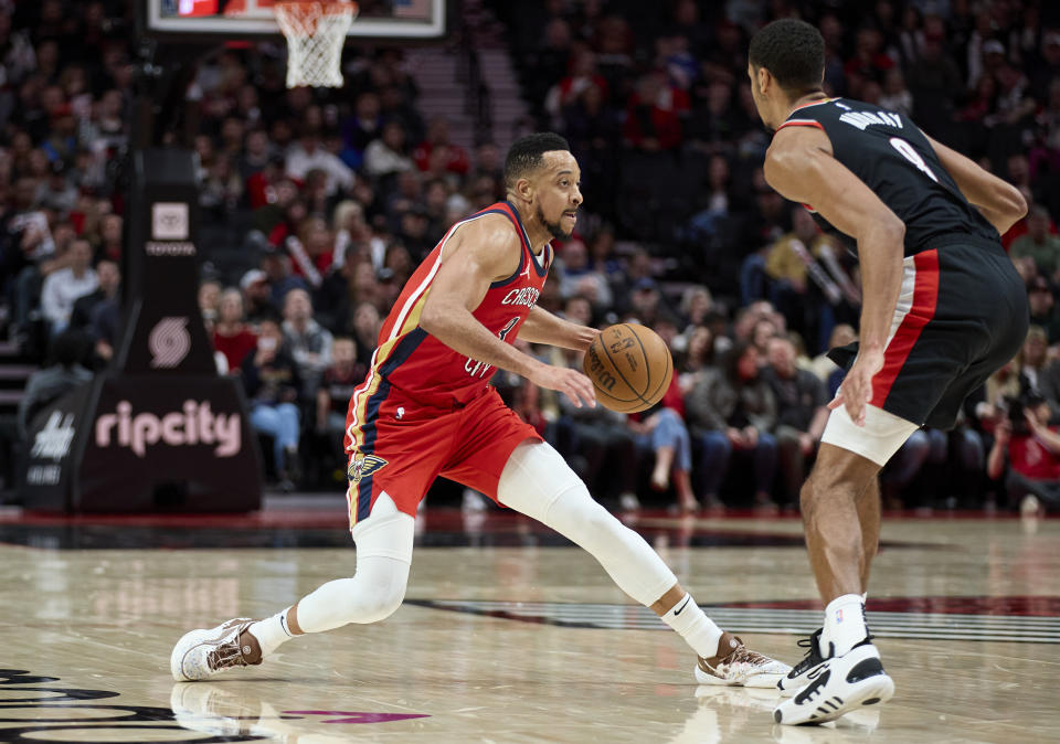 New Orleans Pelicans guard CJ McCollum, left, dribbles around Portland Trail Blazers forward Kris Murray during the second half of an NBA basketball game in Portland, Ore., Tuesday, April 9, 2024. (AP Photo/Craig Mitchelldyer)