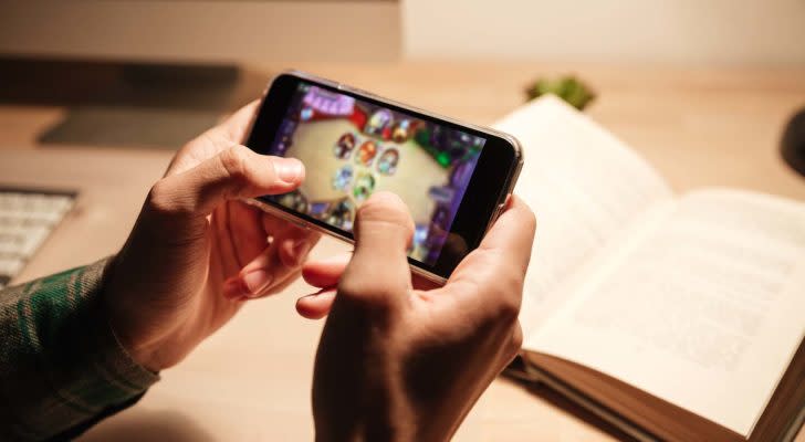 A close-up shot of hands playing a video game on a mobile phone.