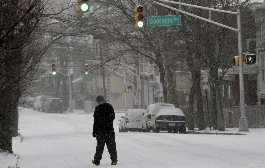 A man walks on a snow covered street, Tuesday, Jan. 21, 2014, in Jersey City, N.J. A storm is expected to hit the northern New Jersey region throughout the day. Because of hazardous driving conditions New Jersey Gov. Chris Christie's inauguration party at Ellis Island was cancelled. (AP Photo/Julio Cortez)