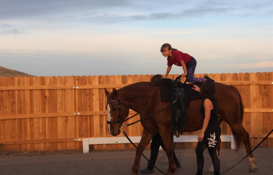 Alexis Fiedler walks alongside her young student as she practices the early stages of equestrian vaulting with the Hope Falls Vaulting Club.