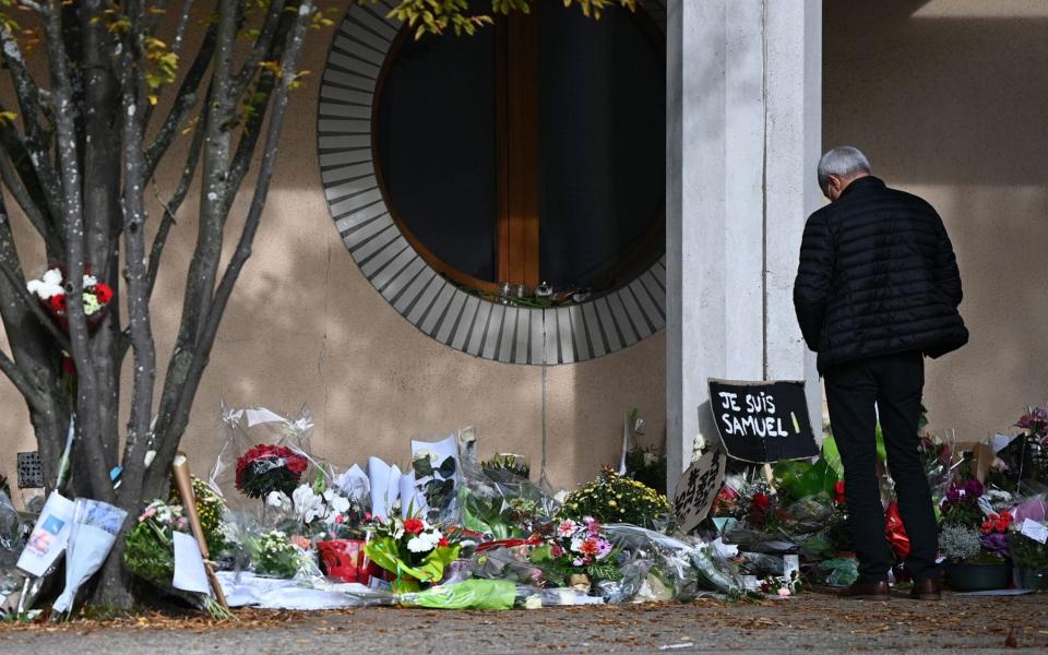  A man looks at flowers layed outside the Bois d'Aulne secondary school in homage to slain history teacher Samuel Paty - AFP