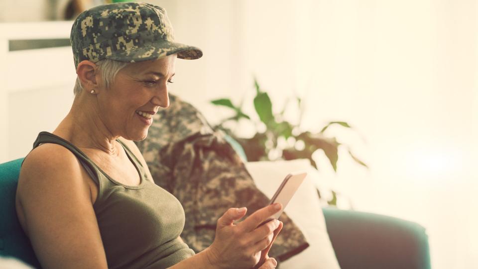 Military mature woman using smart phone at home.