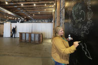 Stephanie Skoglund touches up paint on a giant chalk board where guests can leave messages for the bride and groom at The Vault, the wedding and event center she owns in Tenino, Wash., on July 1, 2020. The board still bears the names — Kyzer and Sandra — of the last couple to be married at the venue in March before the coronavirus outbreak forced them to close their doors. (AP Photo/Ted S. Warren)