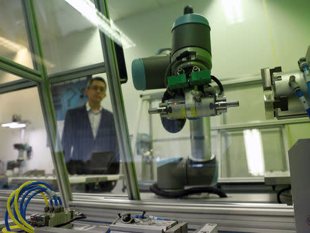 A Universal Robots employee demonstrates how a model of their industrial robot arms works in Singapore March 3, 2017. Picture taken March 3, 2017. REUTERS/Edgar Su