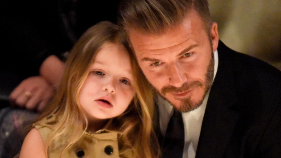 Harper Beckham in 2015 at the Burberry runway show with Dad David 