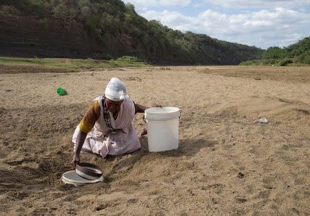 A woman gets water from a well dug in the Black Imfolozi River bed, which is dry due to drought, near Ulundi, northeast of Durban, South Africa. REUTERS/Rogan Ward