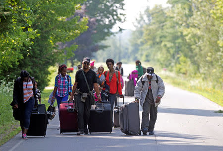 FILE PHOTO: Three families that claimed to be from Burundi walk down Roxham Road to cross into Quebec at the US-Canada border in Champlain, New York, U.S., August 3, 2017. REUTERS/Christinne Muschi/File Photo