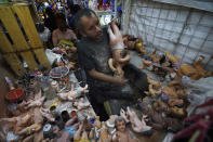 Maximino Vértiz Quintanilla repara la estatua del niño Dios de un cliente dentro de su tienda en preparación para la fiesta del "Día de la Candelaria" en la Ciudad de México, el miércoles 25 de enero de 2023. (AP Foto/Marco Ugarte)