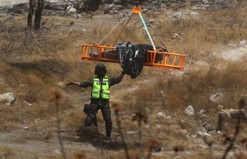 Forensic experts work with several bags of human remains extracted from the bottom of a ravine