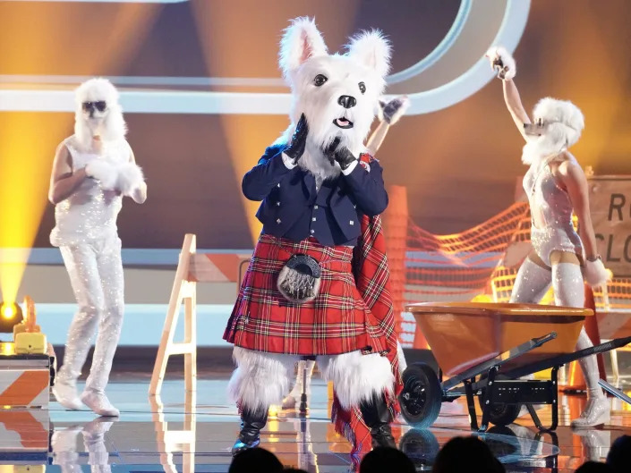mcterrier, a person wearing a scottish terrier costume and a kilt singing onstage on the masked singer