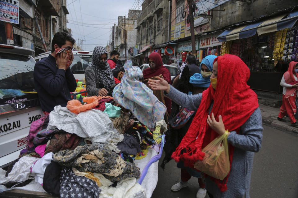 Indians, some of them, wearing face masks as a precautionary measure against the coronavirus shop at a Sunday market in Jammu, India, Sunday, Jan.3, 2021. India authorized two COVID-19 vaccines on Sunday, paving the way for a huge inoculation program to stem the coronavirus pandemic in the world’s second most populous country. (AP Photo/Channi Anand)