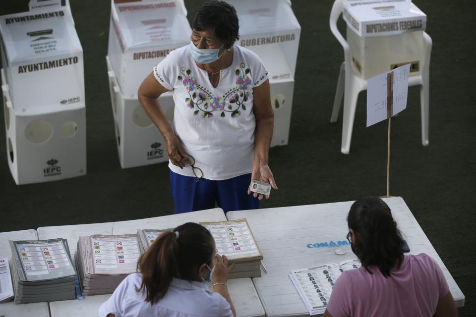 A woman shows her ID before voting in Acapulco, Mexico, Sunday, June 6, 2021. Mexicans are electing the entire lower house of Congress, almost half the country's governors and most mayors. (AP Photo/Fernando Llano)