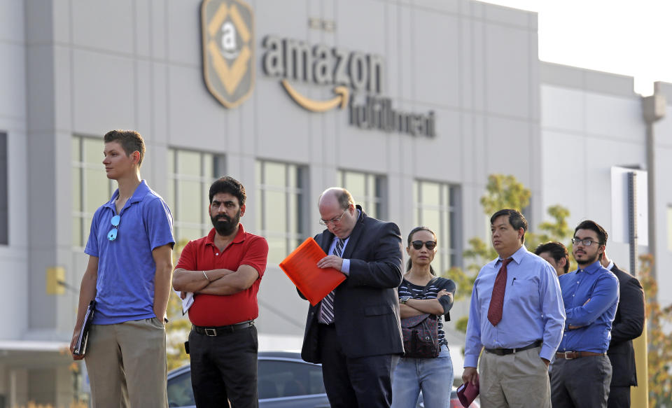 People wait in a line of about one hundred applicants waiting to enter a job fair Wednesday, Aug. 2, 2017, at an Amazon fulfillment center, in Kent, Wash. Amazon plans to make thousands of job offers on the spot at nearly a dozen U.S. warehouses during the recruiting event. (AP Photo/Elaine Thompson)