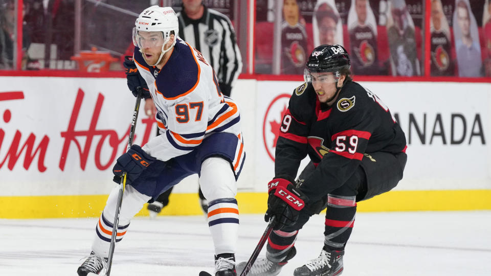 OTTAWA, ON - APRIL 7:  Connor McDavid #97 of the Edmonton Oilers skates up ice with the puck against Alex Formenton #59 of at Canadian Tire Centre on April 7, 2021 in Ottawa, Ontario, Canada.  (Photo by AndrÃ© Ringuette/NHLI via Getty Images)