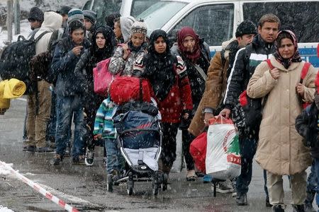 Migrants stand in queue during snowfall before passing Austrian-German border in Wegscheid in Austria, near Passau November 22, 2015. REUTERS/Michael Dalder/Files