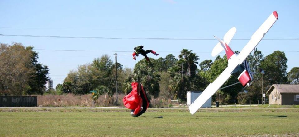 This photo released by the Polk County Sheriff's Office shows a plane nose-diving into the ground after getting tangled with a parachutist, left, Saturday March 8, 2014, at the South Lakeland Airport in Mulberry, Fla. Both the pilot and jumper hospitalized with minor injuries. (AP Photo/Polk County Sheriff's Office, Tim Telford) MANDATORY CREDIT