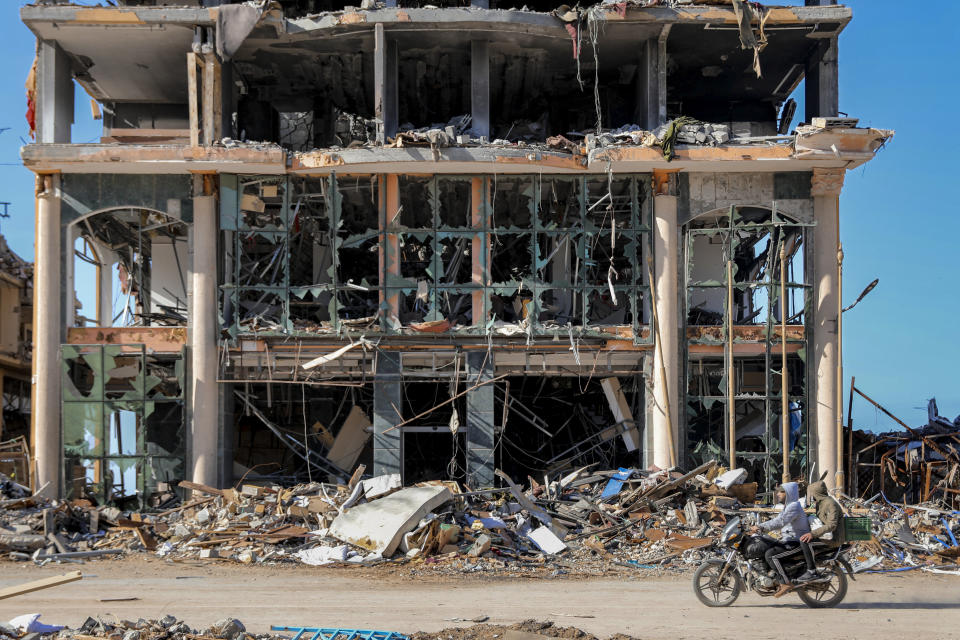 Palestinians ride a motorcycle by a destroyed building in Gaza City on Wednesday, Nov. 29, 2023, the sixth day of the temporary cease-fire between Hamas and Israel. (AP Photo/Mohammed Hajjar)