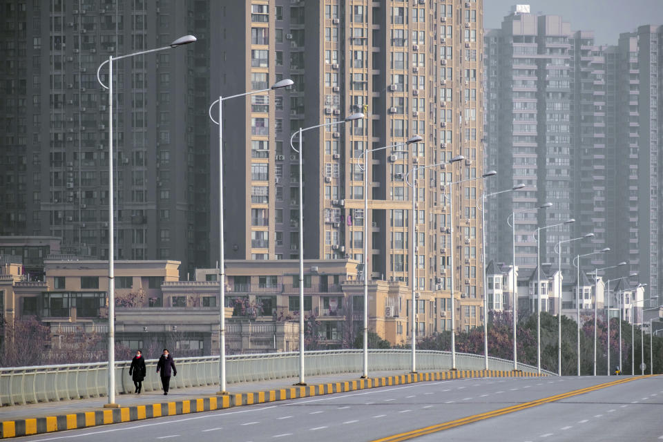 FILE - In this Jan. 28, 2020, file photo, people wearing face masks walk down a deserted street in Wuhan in central China's Hubei Province. As the coronavirus spreads around the world, International health authorities are hoping countries can learn a few lessons from China, namely, that quarantines can be effective and acting fast is crucial. On the other hand, the question before the world is to what extent it can and wants to replicate China’s draconian methods. (AP Photo/Arek Rataj, File)