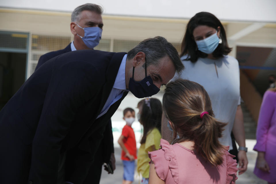Greece's Prime Minister Kyriakos Mitsotakis speaks to a pupil, during the start of the new school year in Athens, Monday, Sept. 14, 2020. Schools opened in Greece on Monday amid concerns due to a new spike in coronavirus infections and along with resistance by some parents to a regulation stipulating that all children and adults must wear protective face masks. (AP Photo/Thanassis Stavrakis, Pool)
