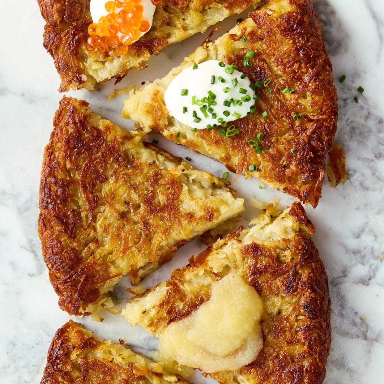 large latke in a skillet with applesauce, caviar, creme fraiche