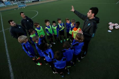 Boys from the RCD Espanyol soccer academy listen to their coach during a training session at Dani Jarque training camp in Sant Adria de Besos, near Barcelona, Spain February 20, 2017. REUTERS/ Albert Gea/Files