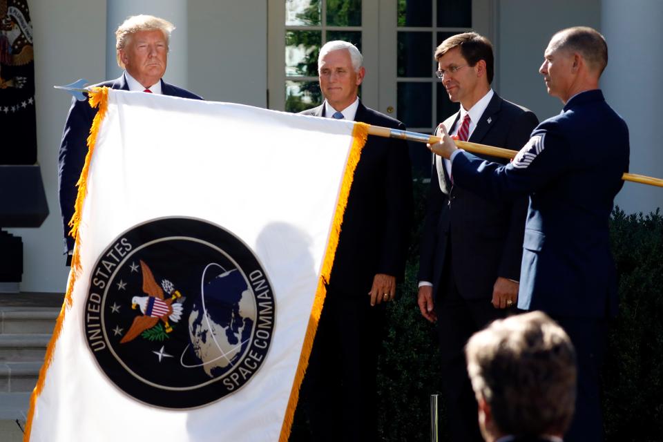FILE - In this Aug. 29, 2019, file photo, President Donald Trump, left, watches with Vice President Mike Pence and Defense Secretary Mark Esper as the flag for U.S. space Command is unfurled as Trump announces the establishment of the U.S. Space Command in the Rose Garden of the White House in Washington. President Joe Biden has decided to keep U.S. Space Command headquarters in Colorado, overturning a last-ditch decision by the Trump administration to move it to Alabama and ending months of politically fueled debate, according to senior U.S. officials. (AP Photo/Carolyn Kaster, File) ORG XMIT: WX108