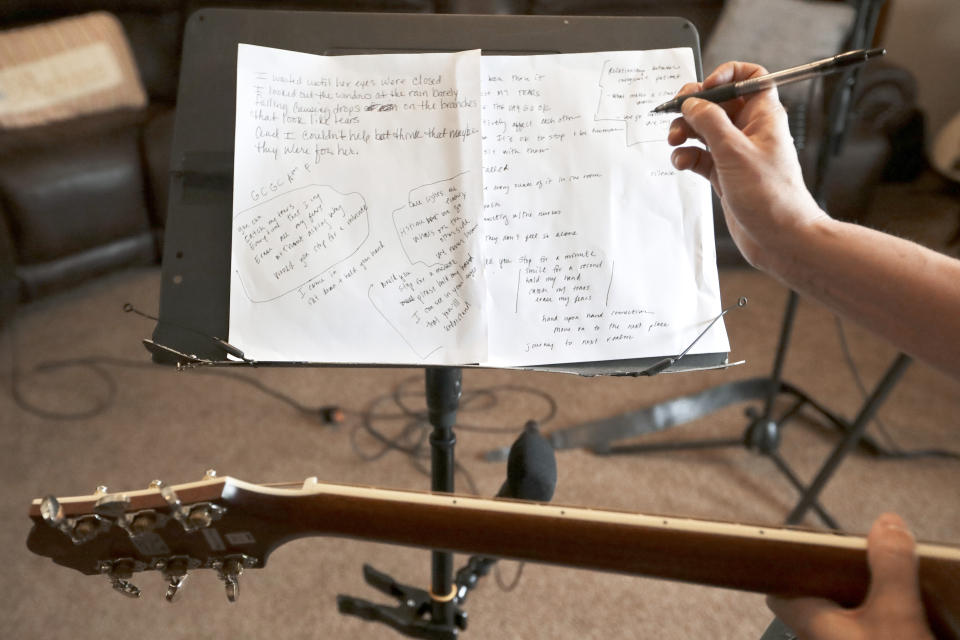 In this May 22, 2020, photo, nurse Megan Palmer writes down lyrics during a songwriting session with care partner Anna Henderson at Henderson's home in Ashland City, Tenn. During the COVID-19 pandemic, their role as caregivers at Vanderbilt University Medical Center has become even more important as hospital visits from family and friends were limited or prohibited to prevent the spread of the virus. Music and songwriting has helped them express the complexity of emotions that comes with caregiving, especially in the time of a pandemic. (AP Photo/Mark Humphrey)