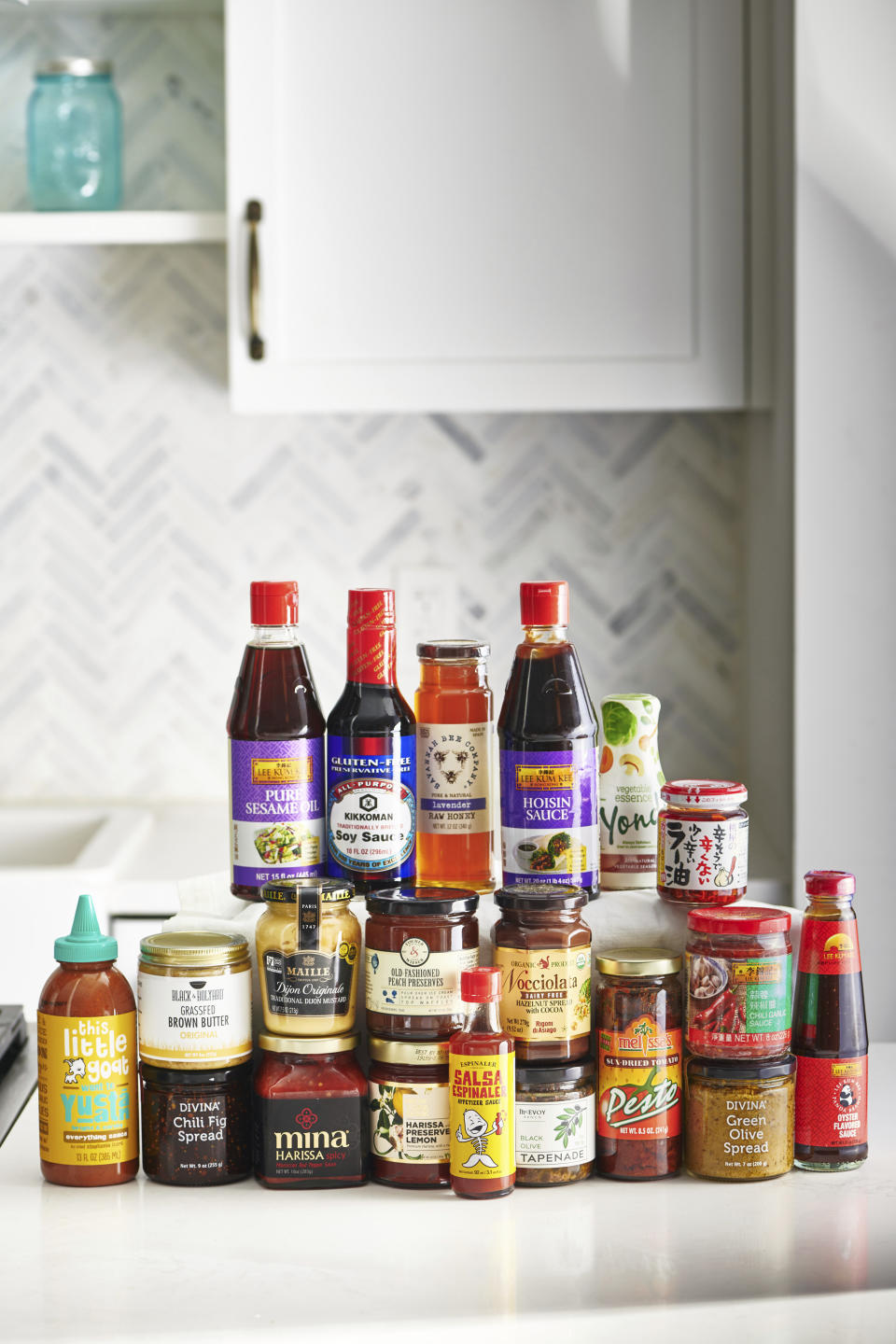 This December 2019 photo provided by Katie Workman shows a variety condiments on a counter in New York. To give your recipe repertoire a boost, pick up a few new condiments such as oyster sauce, Sriracha sauce, and a some fun preserves. (Cheyenne Cohen/Katie Workman via AP)