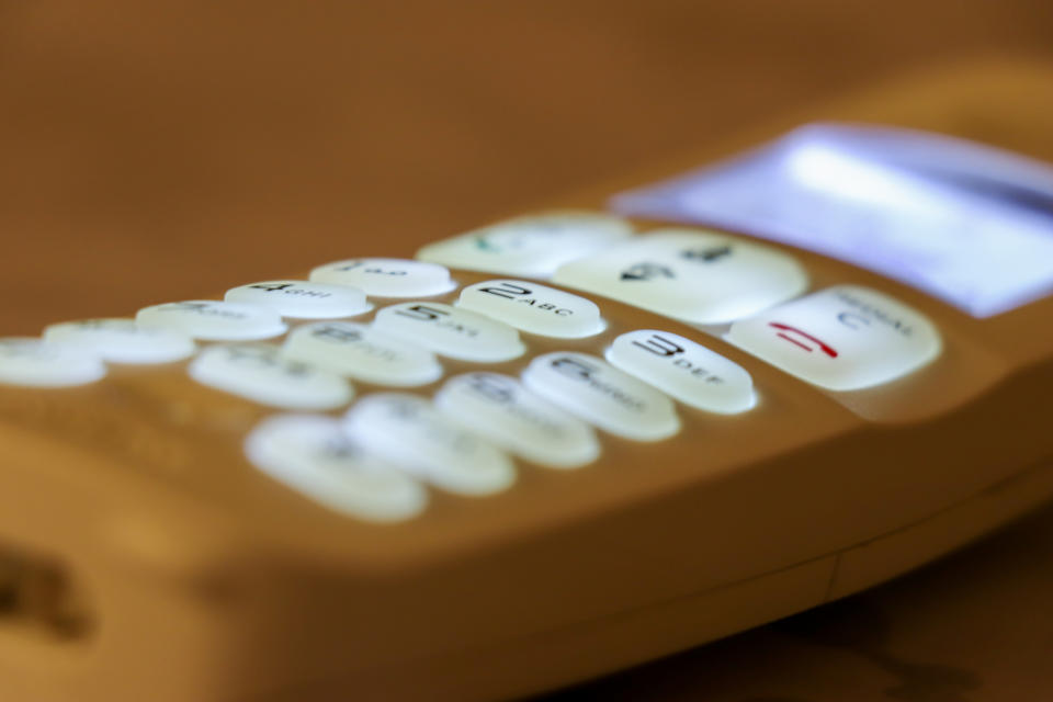 Close-up of a landline phone's illuminated keypad with numbers and symbols visible