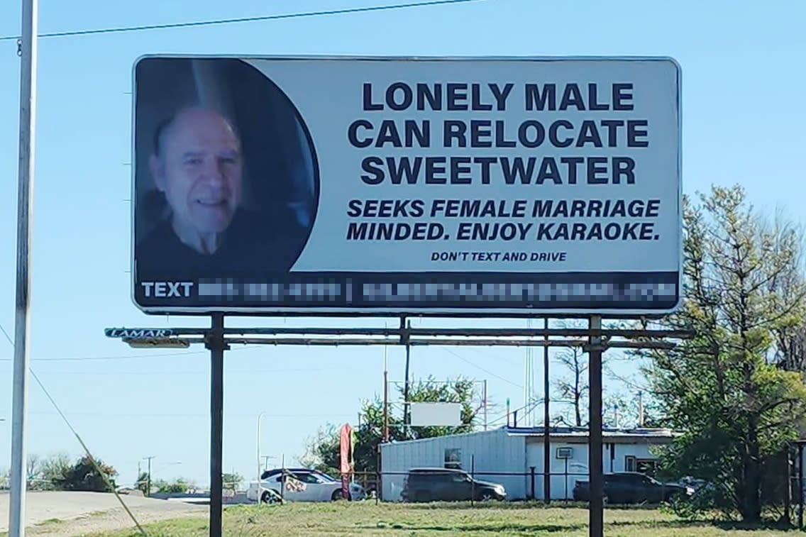 Giant billboard displaying a picture of Al Gilberti, a lonely man seeking love with text asking for a female partner interested in marriage and karaoke.