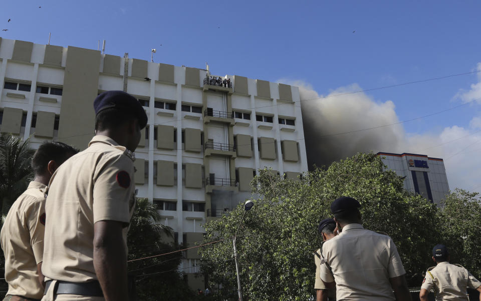 Police men look on as people awaiting rescue stand on the balcony of a nine-story building with offices of a state-run telephone company during a fire in Mumbai, India, Monday, July 22, 2019. (AP Photo/Rafiq Maqbool)