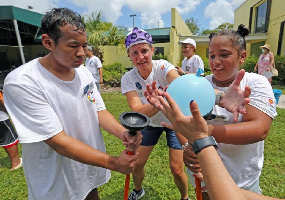 From left: Renzo, Dr. Chryso Katsoufis and McKenzie pass a water-filled balloon to each other at Camp U.O.T.S. on July 23.