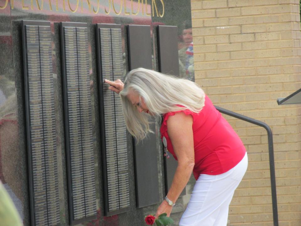Ellen Comfort, points to the name of her son, Capt. Kyle Comfort, before placing a rose at the U.S. Army Special Operations Command Memorial Wall after a ceremony Thursday, May 25, 2023, at Fort Bragg.