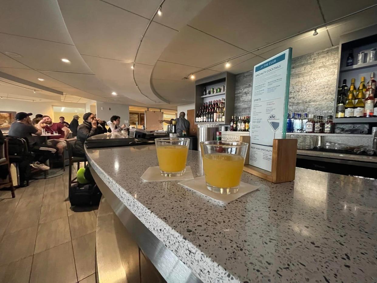 Two orange drinks on a bar at an airport lounge.