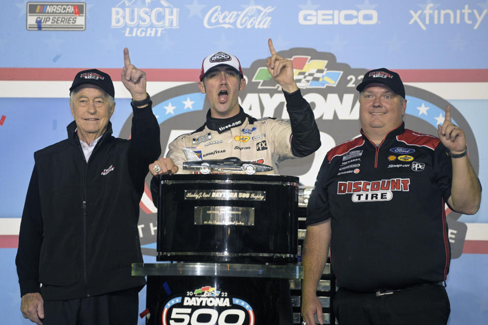 Austin Cindric, center, celebrates in Victory Lane with car owner Roger Penske, left, and crew chief Jeremy Bullins after winning the NASCAR Daytona 500 auto race at Daytona International Speedway, Sunday, Feb. 20, 2022, in Daytona Beach, Fla. (AP Photo/Phelan M. Ebenhack)