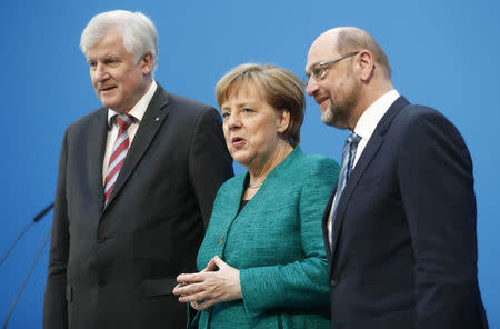Christian Democratic Union (CDU) leader and German Chancellor Angela Merkel, Christian Social Union (CSU) leader Horst Seehofer and Social Democratic Party (SPD) leader Martin Schulz pose after a statement on coalition talks to form a new coalition government in Berlin, Germany, February 7, 2018. REUTERS/Hannibal Hanschke