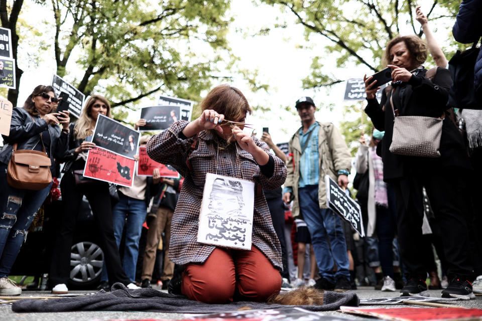 A woman cuts her hair during a demonstration in support of Mahsa Amini in front of the Iranian embassy in Brussels, on September 23, 2022, following the death of an Iranian woman after her arrest by the country's morality police in Tehran.